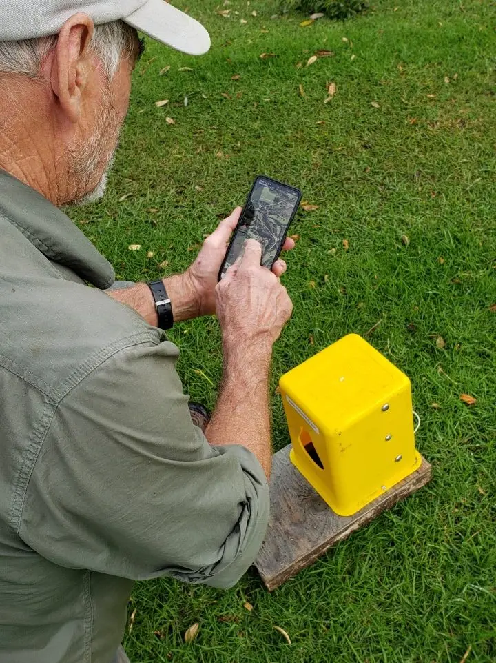 man with phone and possum trap