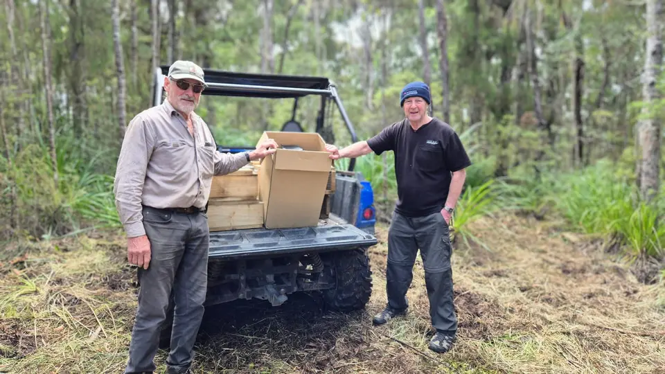 Two volunteers unloading traps from a ute