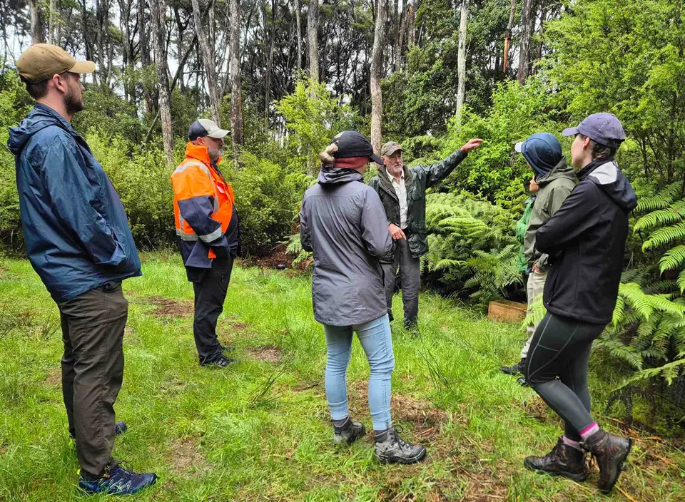A group of volunteers listening to a talk on a ridge track