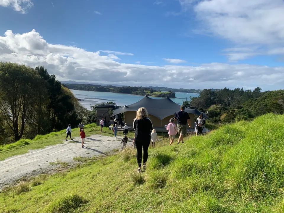 Families walking down a grassy hill towards the estuary on Project Birdsong day